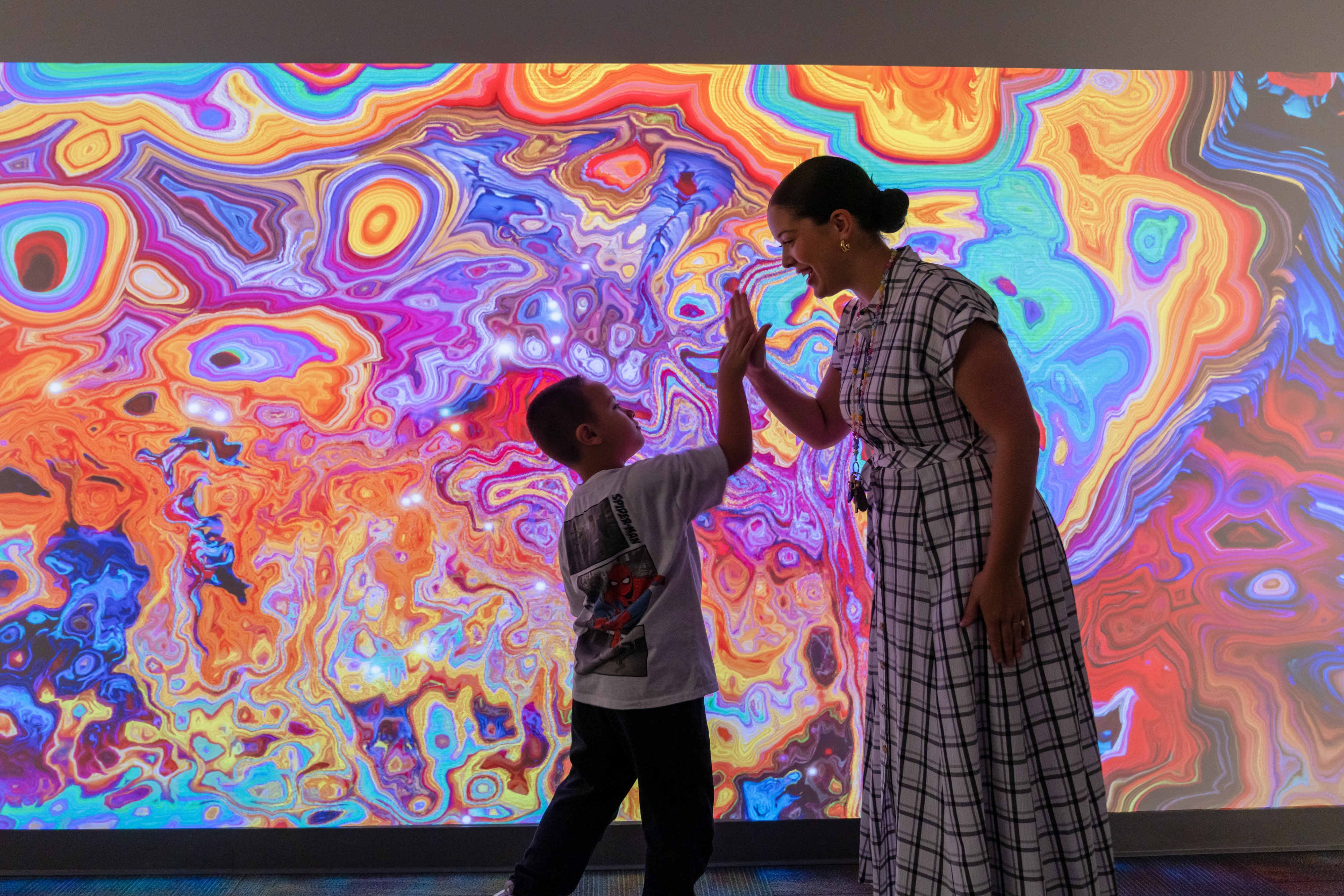 student giving teacher a high five in front of the interactive wall
