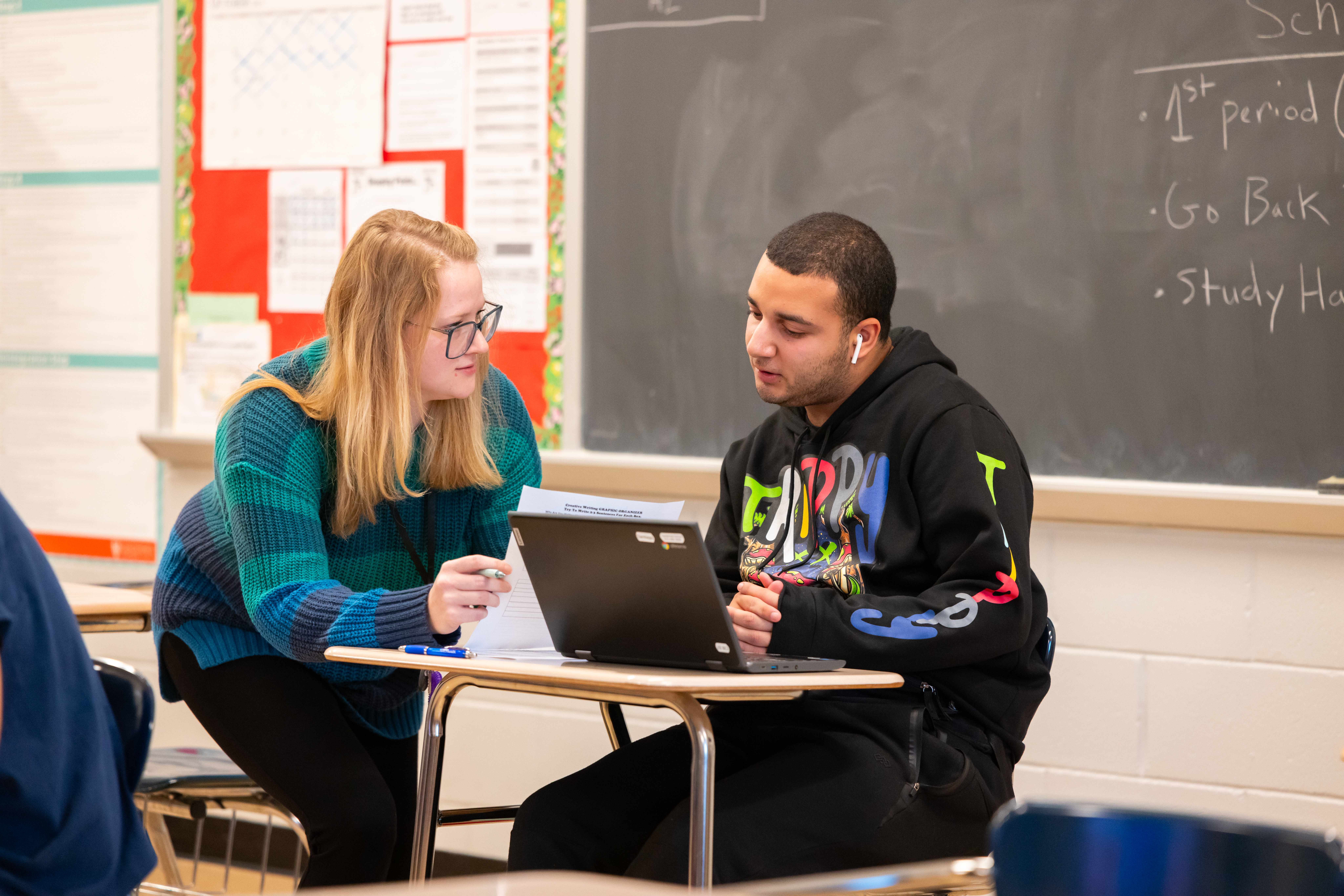 teacher working with student at desk